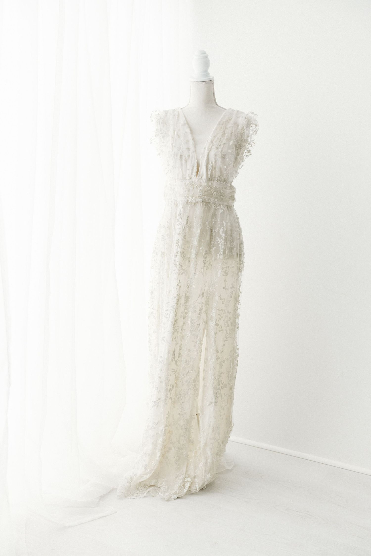 White lace sleeveless maxi dress with floral texture and V-neckline on a mannequin.