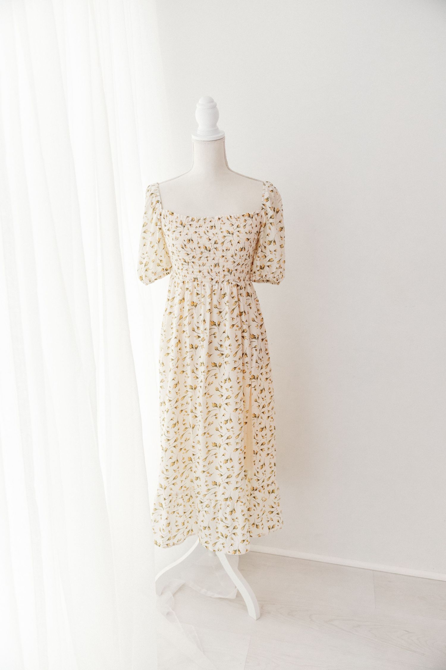 Cream ditsy floral square-neck midi dress with puff sleeves and smocked bodice on mannequin.