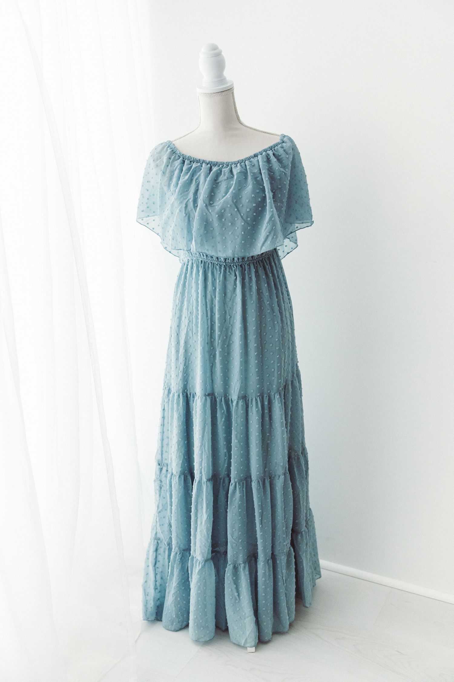Blue off-shoulder lace maxi dress with tiered skirt on a white mannequin.