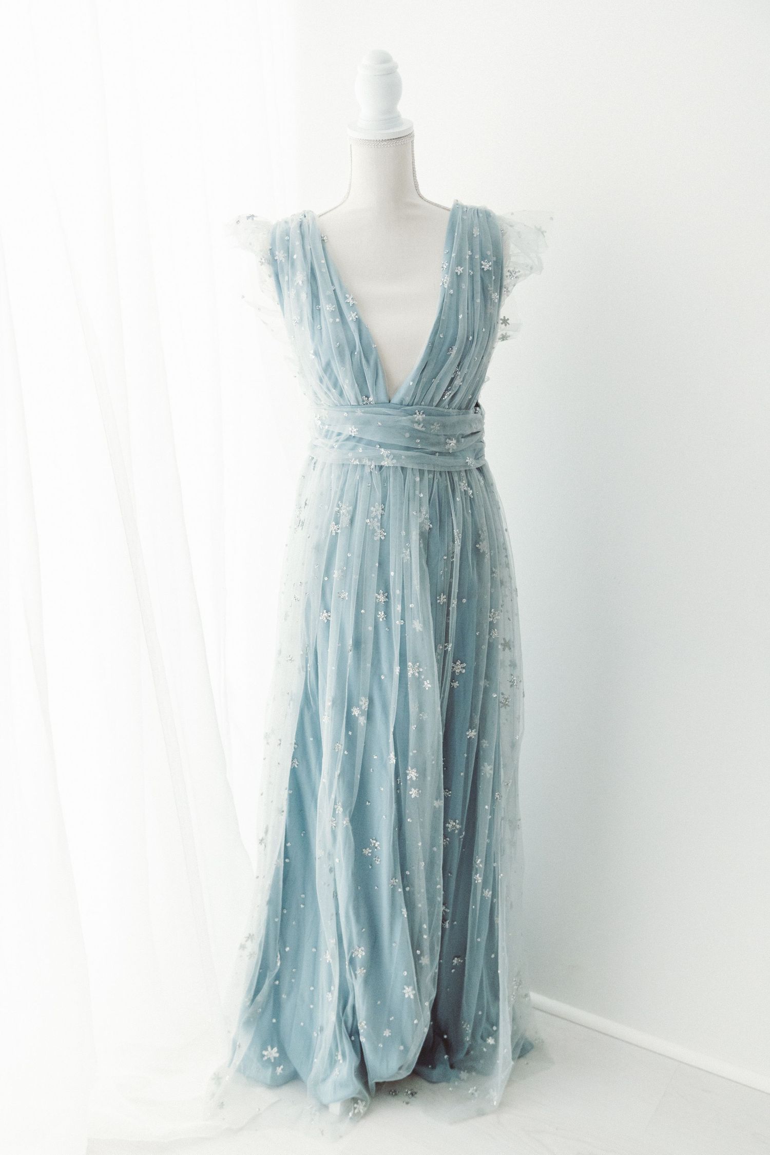 Dusty blue star-embroidered tulle deep V-neck maxi dress on a white mannequin stand.