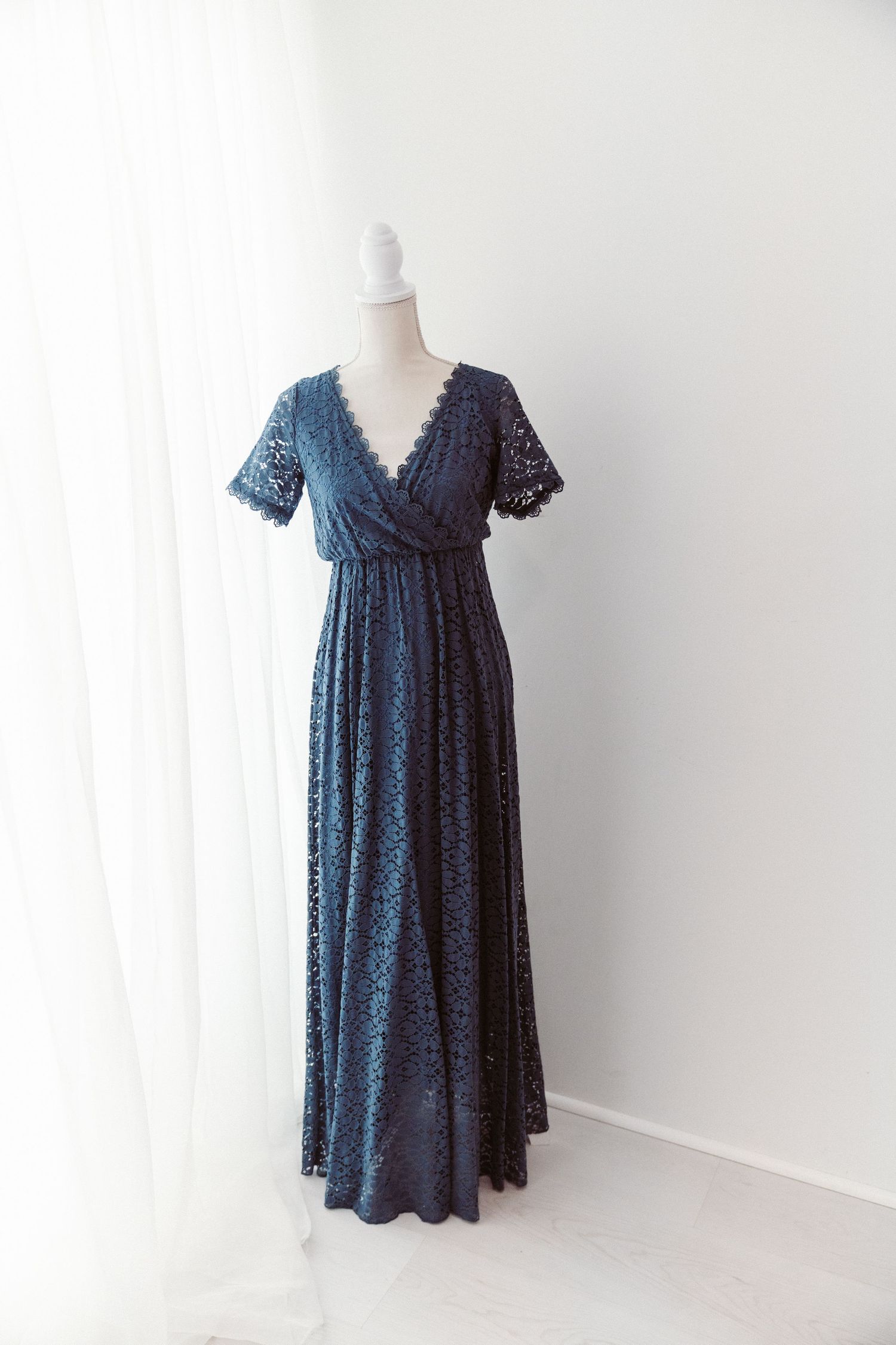 Navy blue lace wrap maxi dress with flutter sleeves on white mannequin.