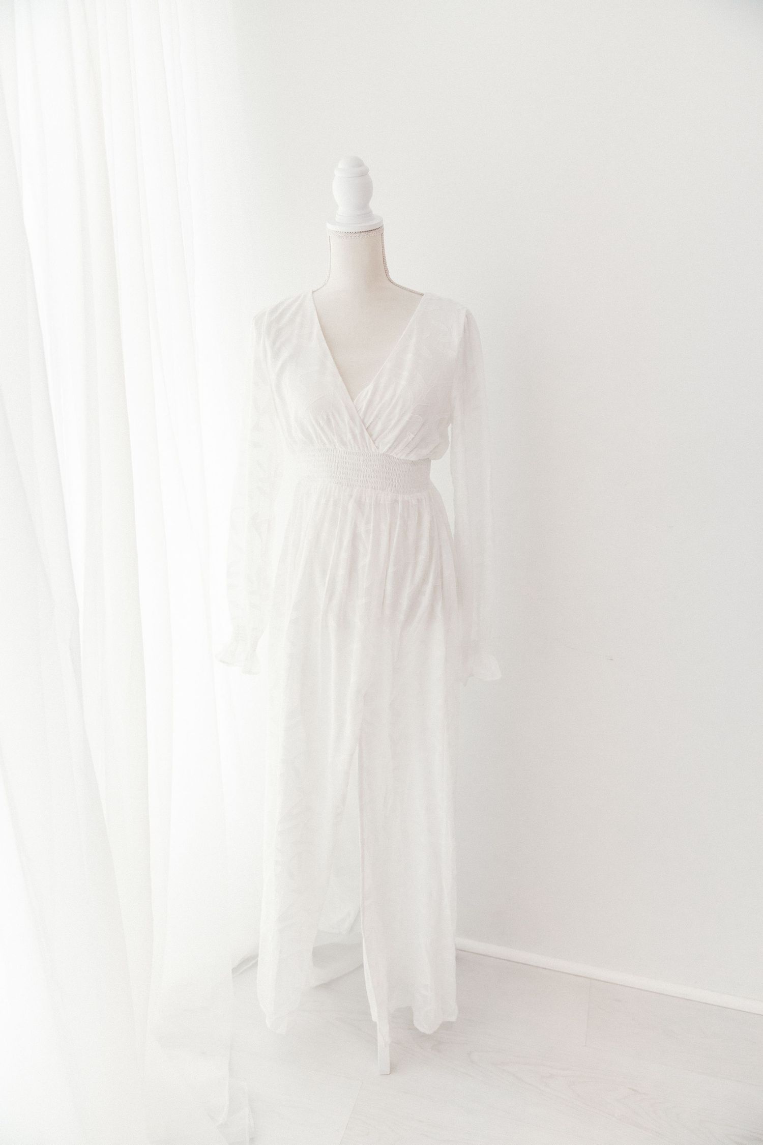 White long sleeve V-neck maxi dress with lace details on white mannequin.