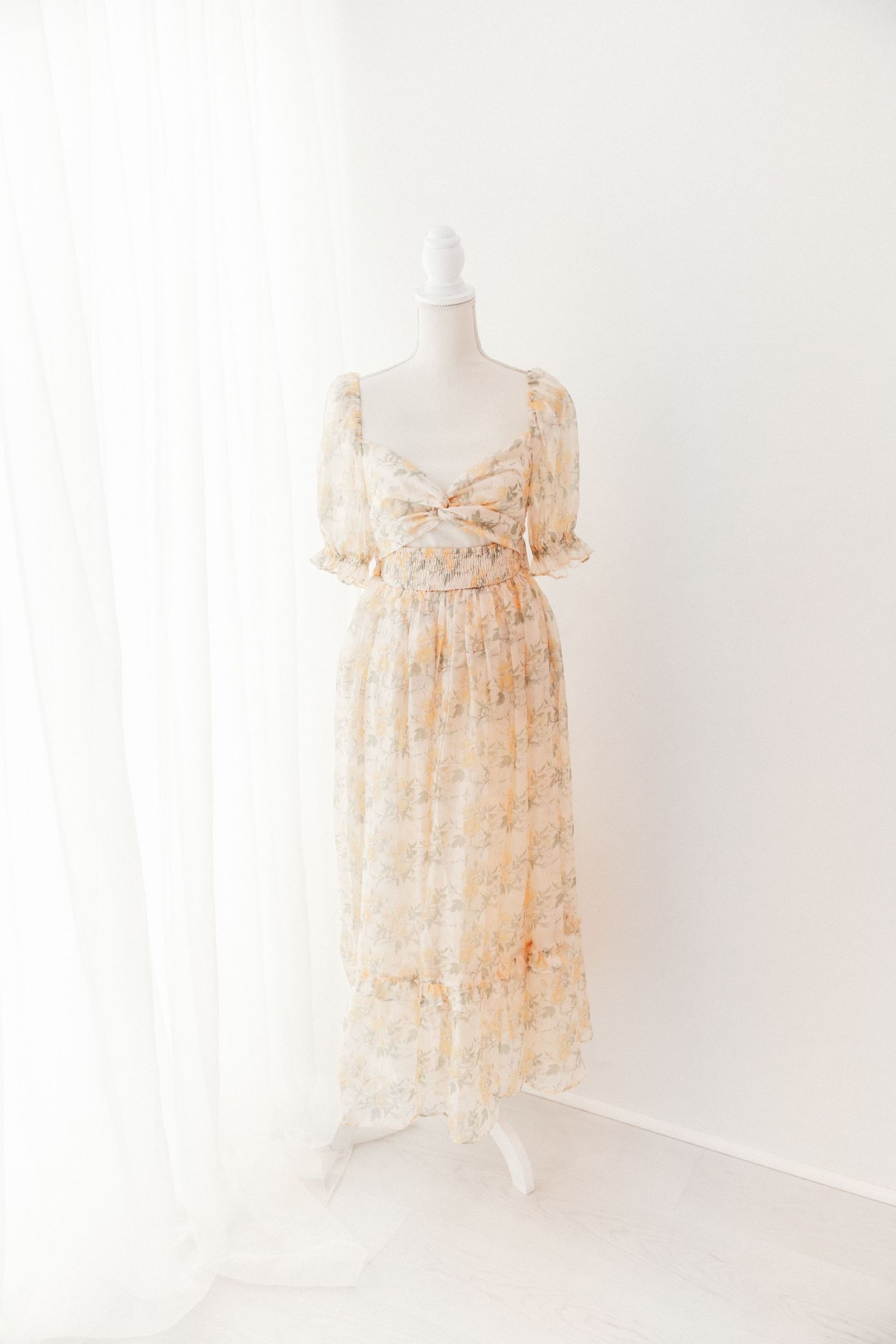 Floral chiffon maternity dress with puff sleeves and empire waist on mannequin.