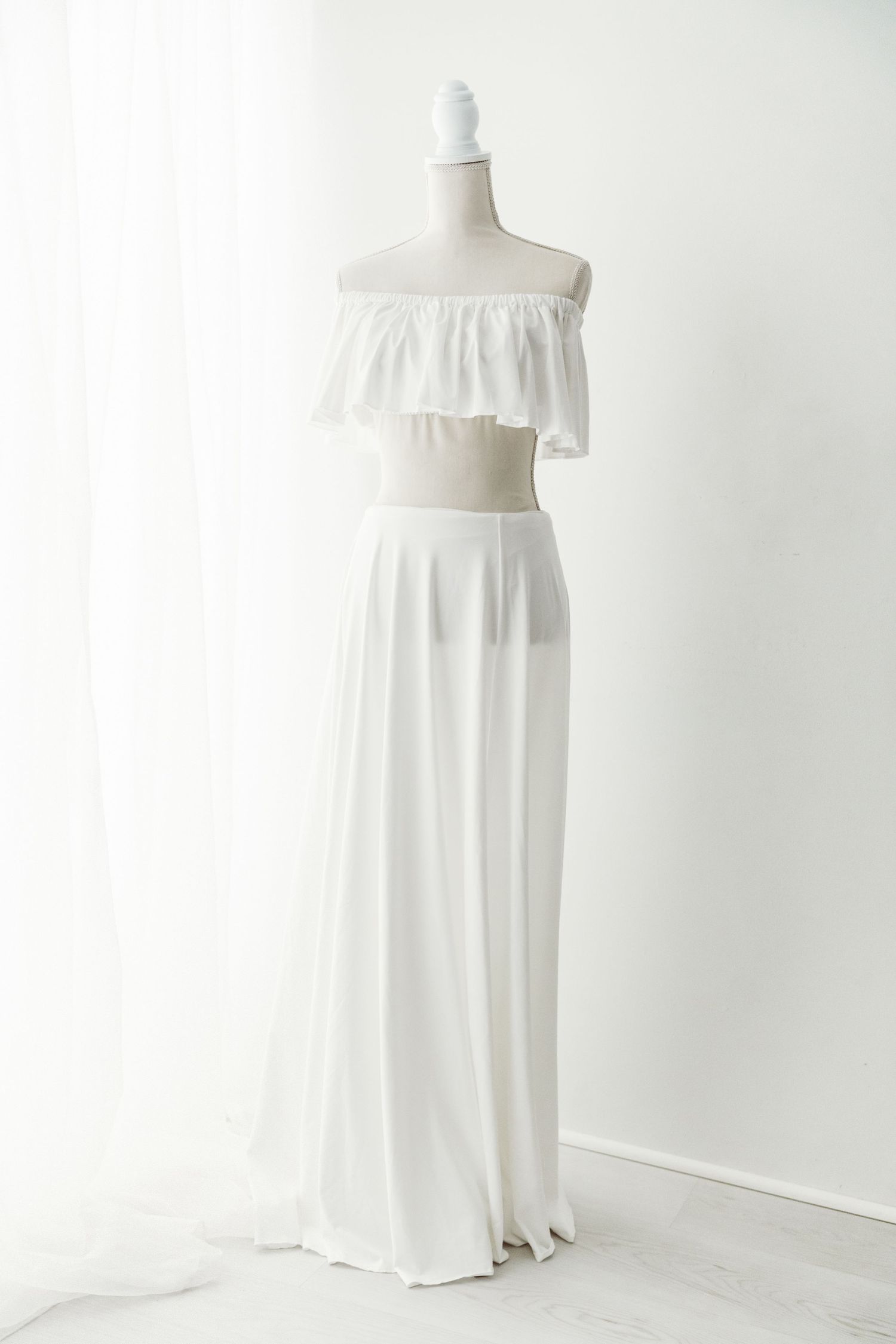 White off-shoulder ruffled crop top and maxi skirt set on mannequin.