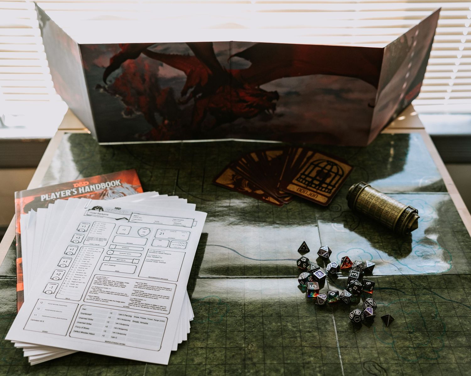a dnd battlemap topped with dice, tarot cards, puzzle box, character sheets, Player's Handbook, and DM screen