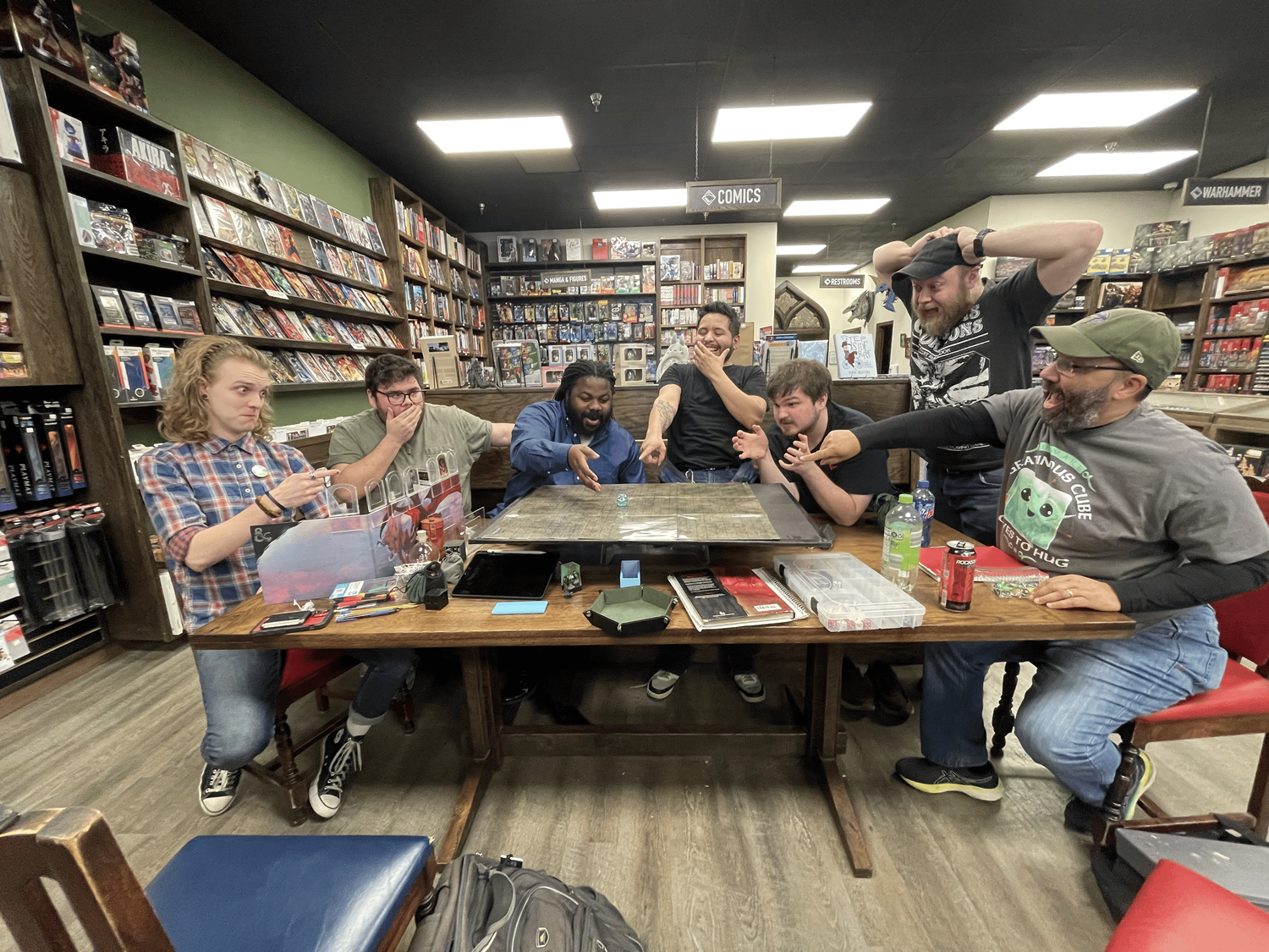 excited dice roll on table surrounded by 7 individuals with various reactions
