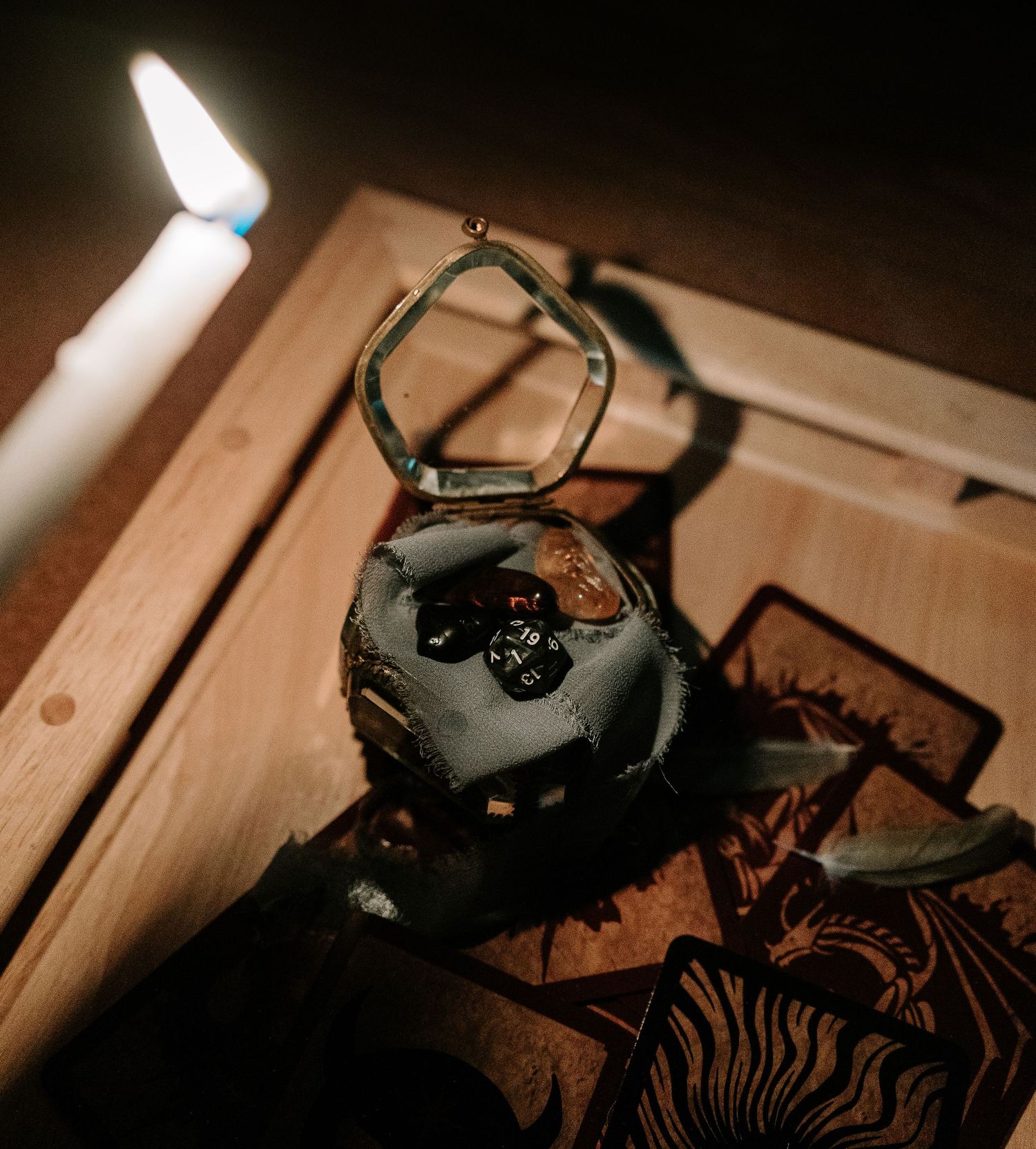 Tarot cards with ambience: lit candle, feathers, dice, antique box with dice and stones inside