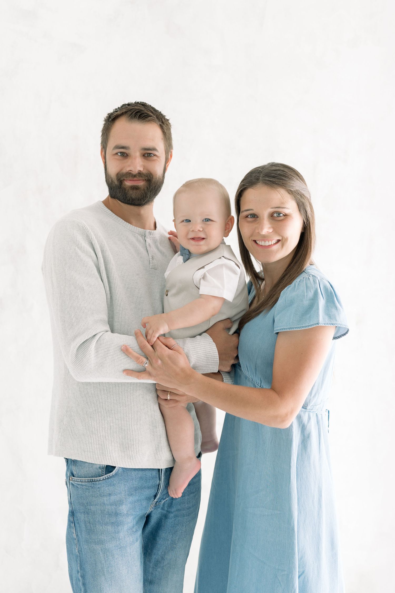 Papa et maman avec leur grand garçon au centre qui regardent fièrement l'objectif pour un portrait de famille
