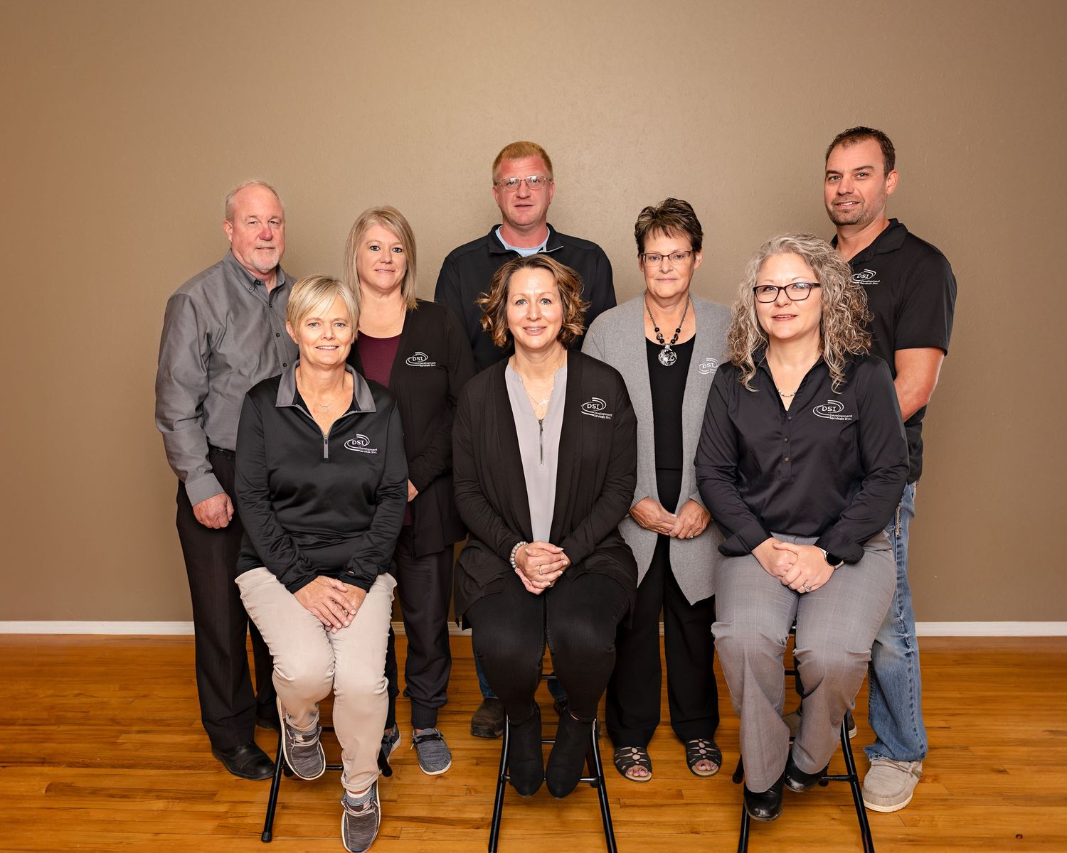 Group portrait of nine DSL company employees in black uniforms posed indoors.