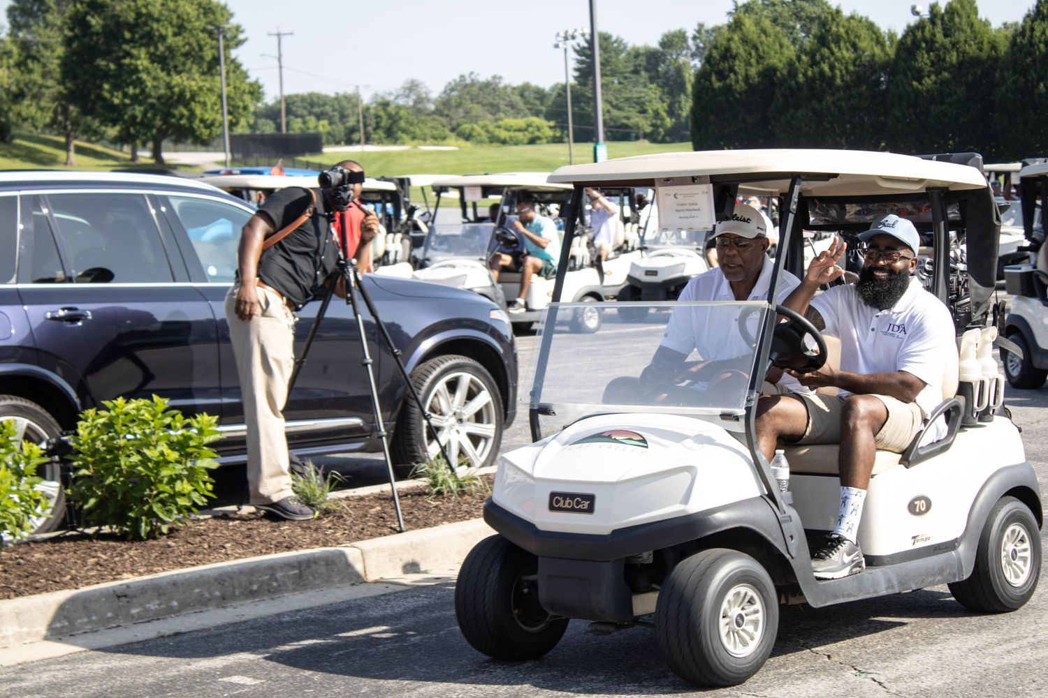 A line of vintage golf carts parked in a row at an outdoor venue on a sunny day.