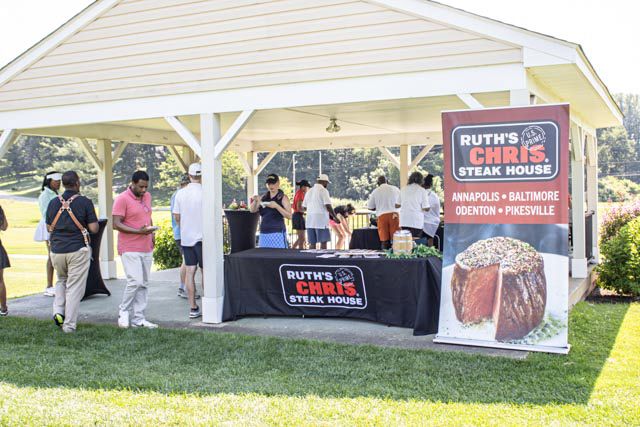 A row of outdoor vendor booths and tents set up at a food festival or farmers market on a sunny day.