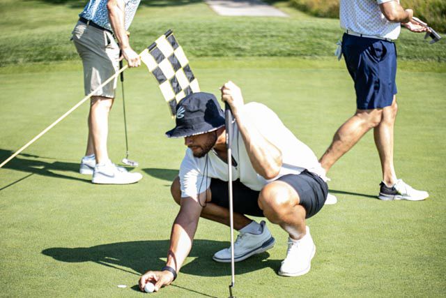 A golfer demonstrates proper putting technique on a green golf course during practice.