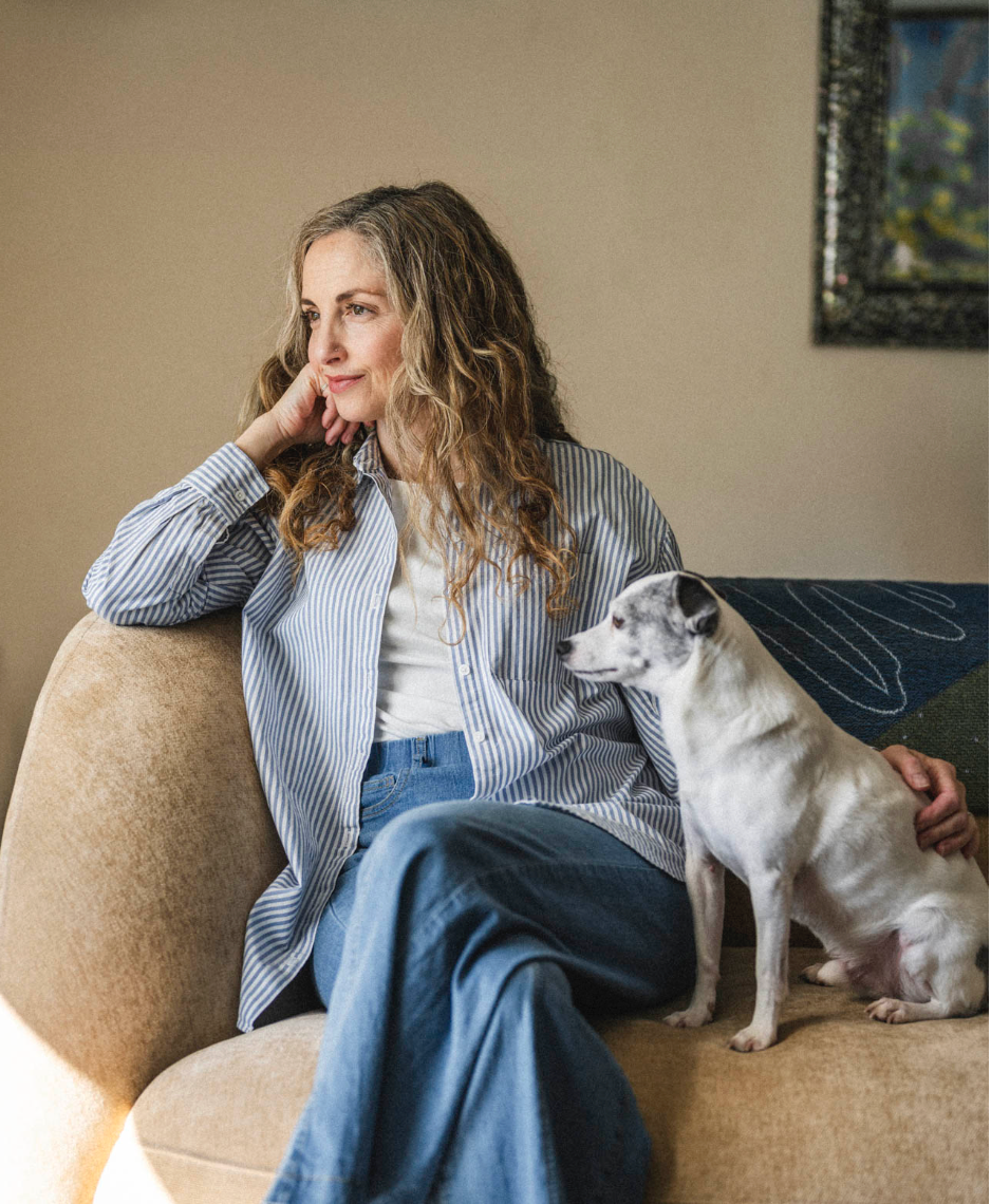 Person in casual clothing relaxing on a beige couch with a white cat companion.