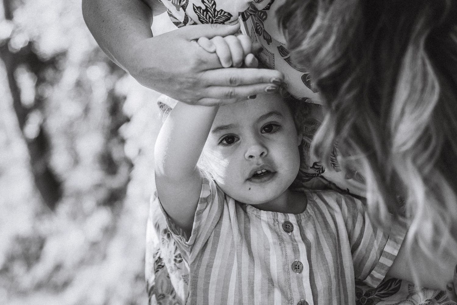 A sweet candid black and white moment showing a child raising their arms in delight.