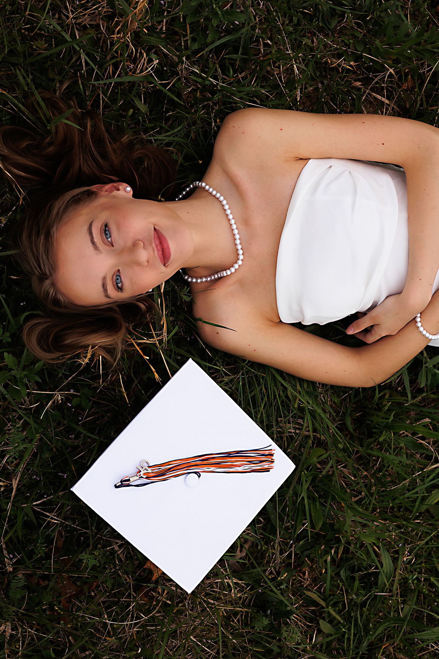 Person in white dress lying on grass next to sketch of a pencil.