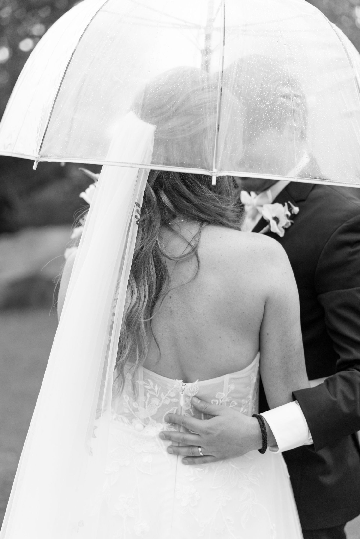 Series of black and white photos showing a couple under a white umbrella on their wedding day.