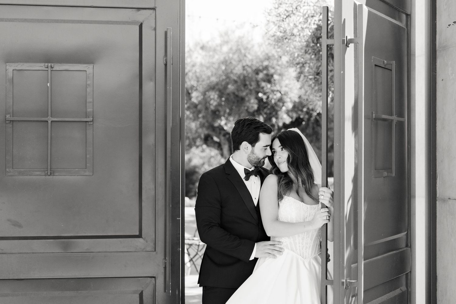 A romantic black and white photo series showing a couple sharing intimate moments in a doorway.