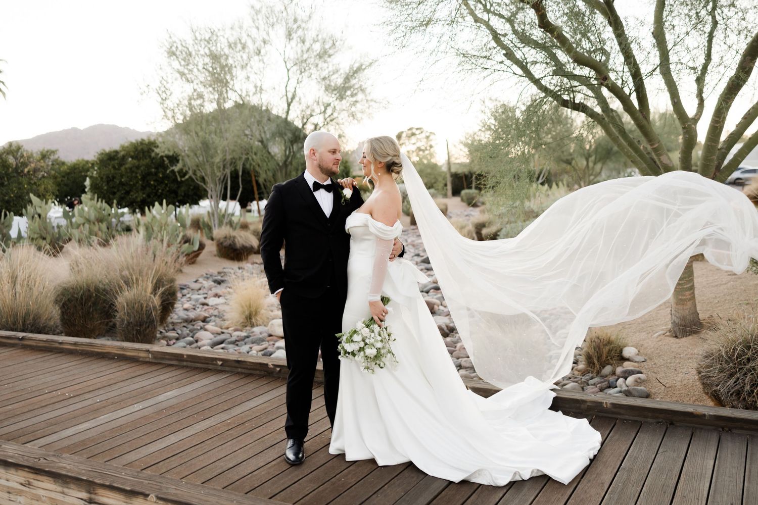 A romantic desert wedding photo series showing intimate moments at an outdoor venue with flowing white dress details.