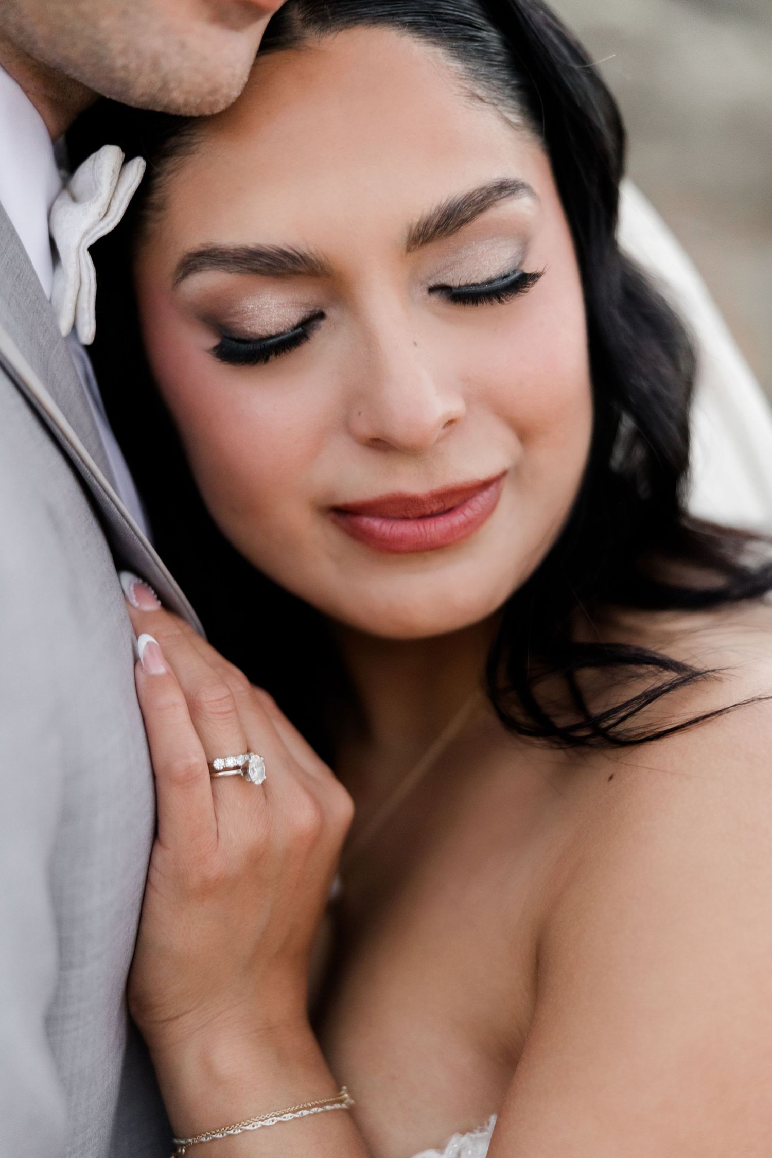Close-up portrait showing delicate bridal makeup and jewelry details.