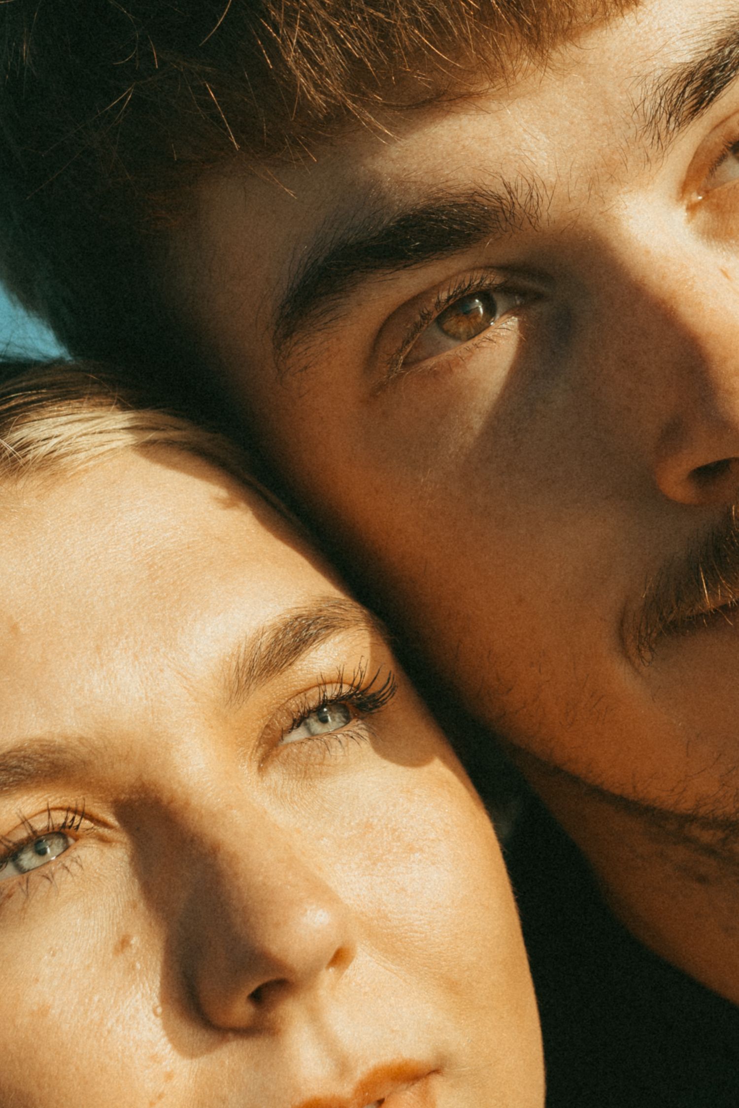 Close-up artistic portrait showing eyes and partial face in warm lighting with dramatic shadows.