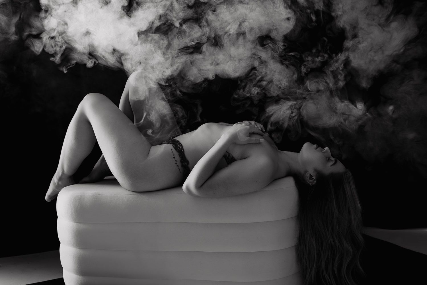 Artistic black and white boudoir photography featuring silhouette in bathtub with smoke effects.