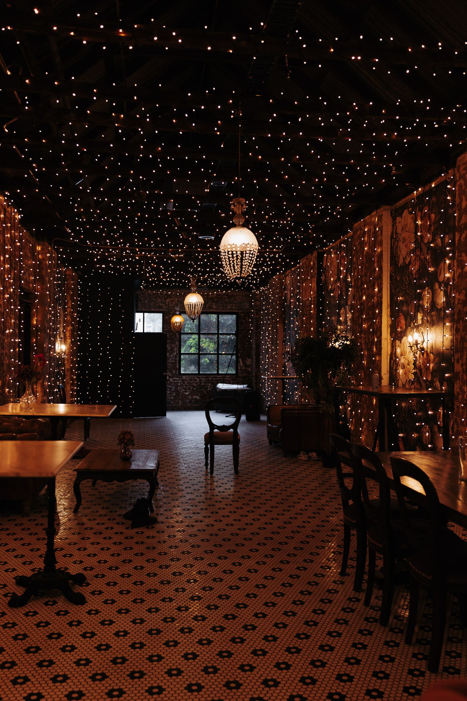 A dimly lit restaurant interior with twinkling string lights overhead and patterned tile flooring creates a cozy atmosphere.