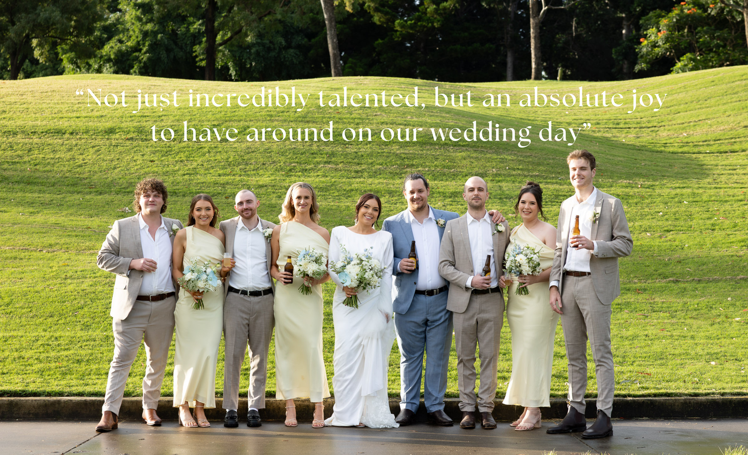 A wedding party wearing khaki pants and white shirts poses outdoors on a sunny day in a grassy field.