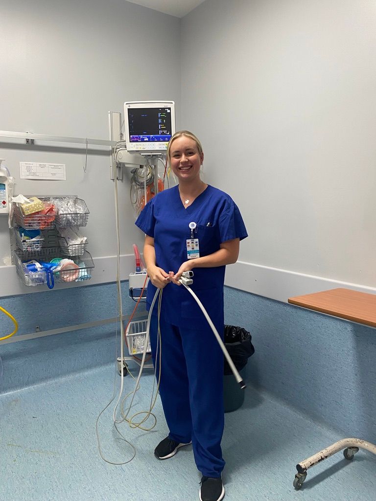 Medical staff in blue scrubs cleaning and sanitizing the floor of a hospital room with cleaning equipment.
