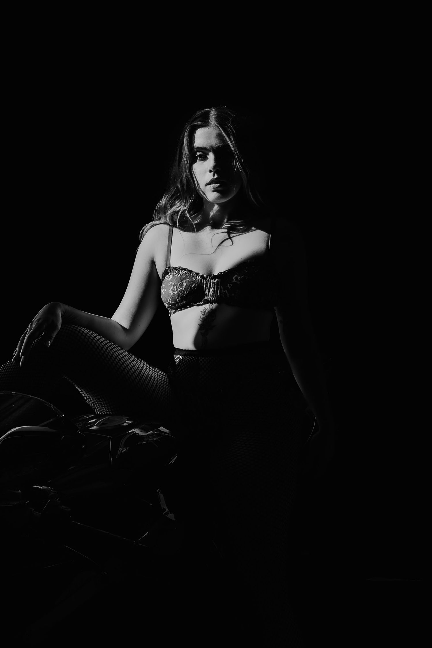 High contrast black and white artistic portrait in lingerie against dark background.