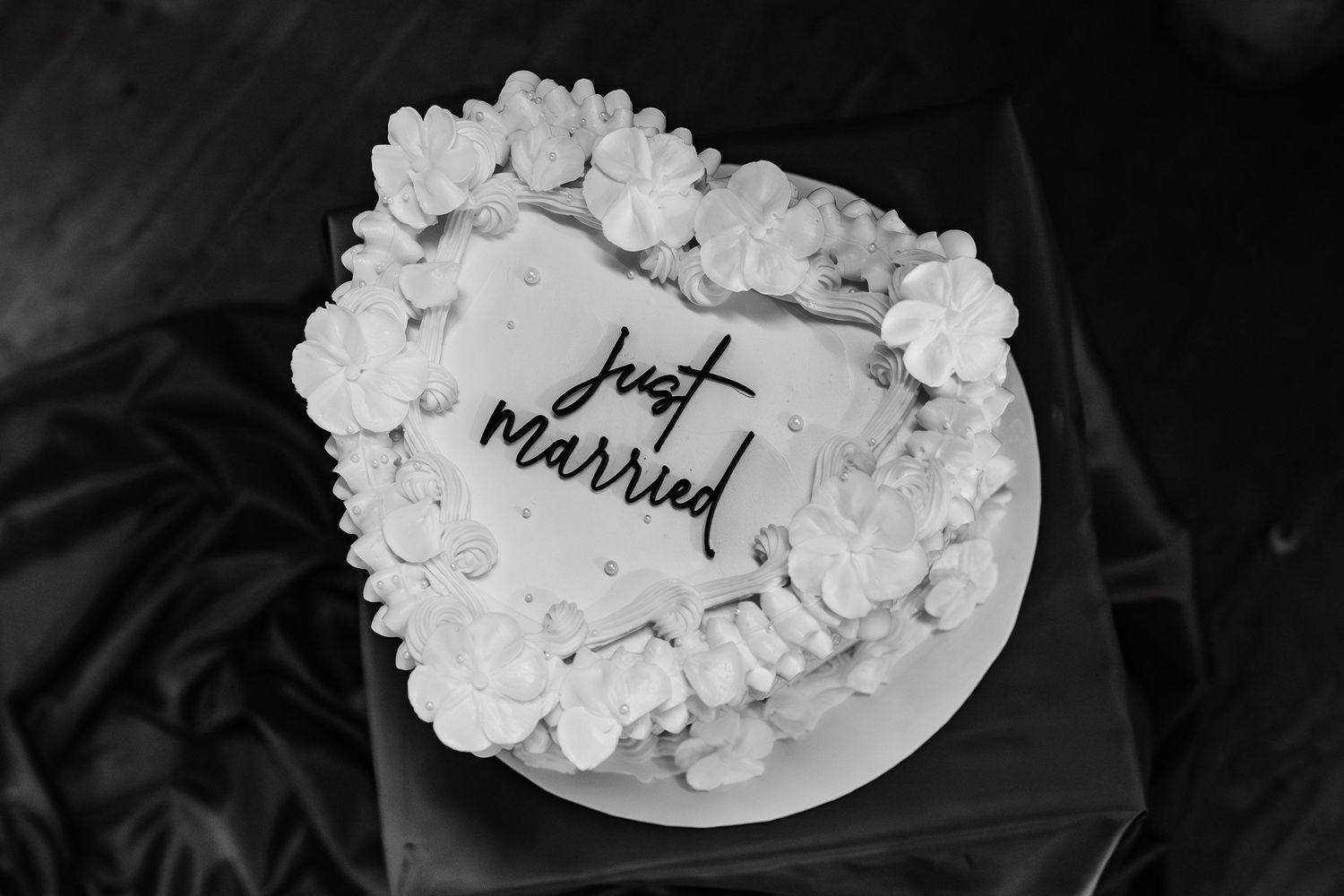 Black and white photograph of elegantly decorated wedding cakes lined up in a row with delicate frosting details.