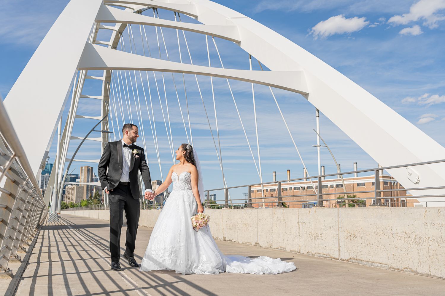 A couple walking on the geometric white bridge at the iconic Milwaukee Art Museum on their wedding day.