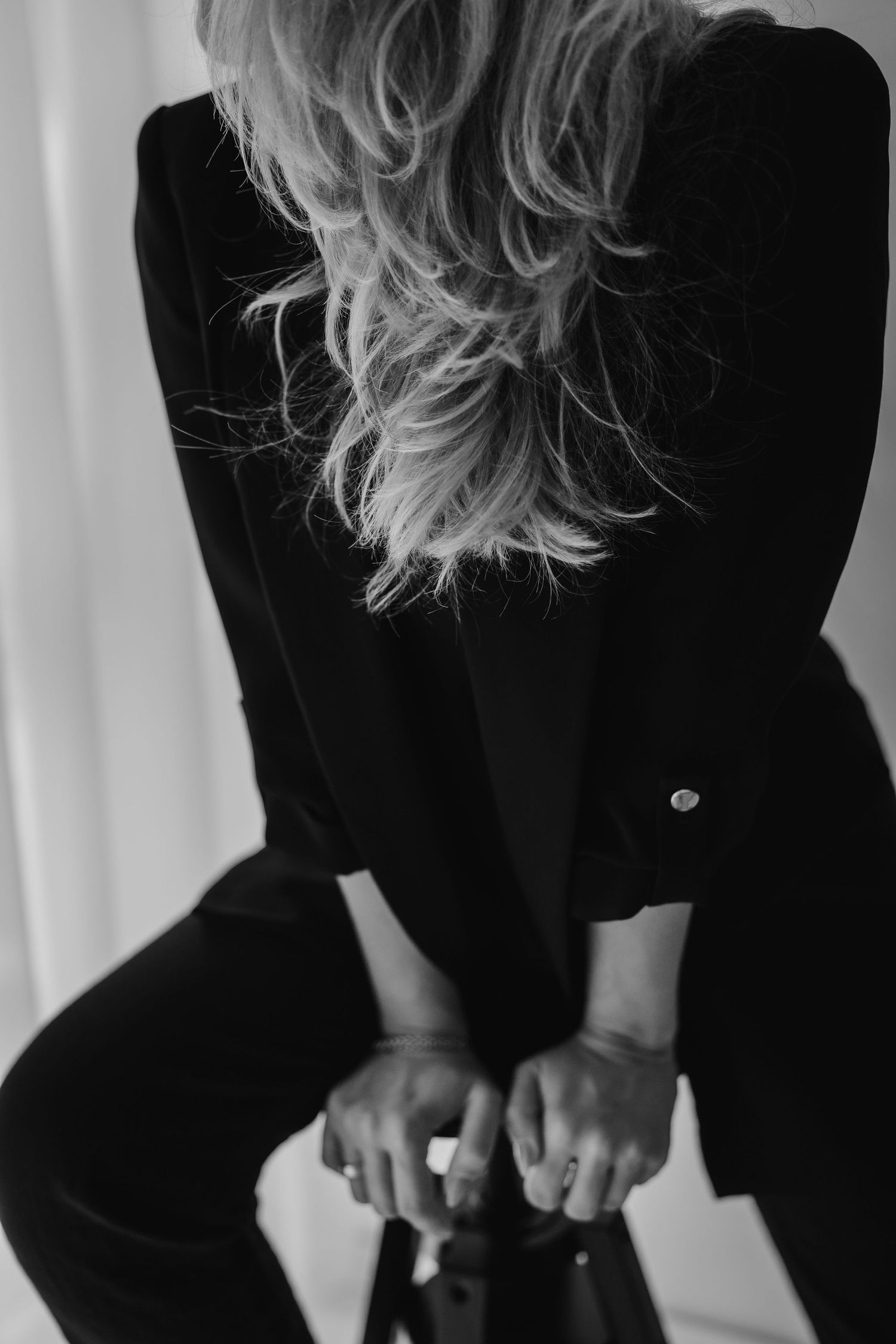 A series of five black and white images showing a person with blonde hair wearing a black top against a light background.