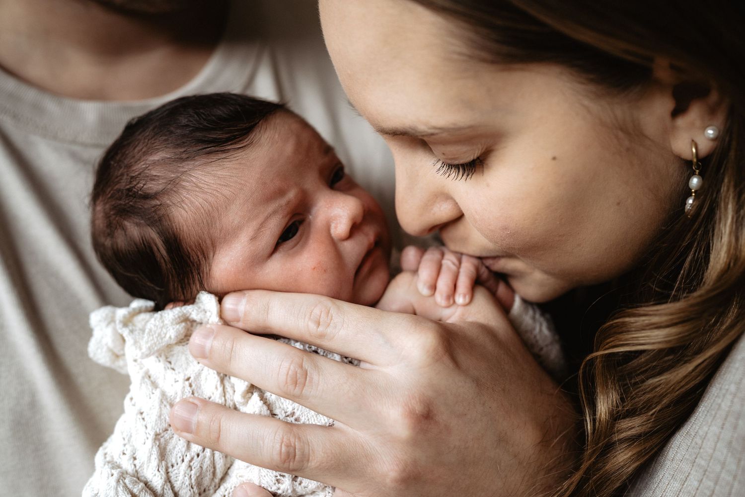 A tender moment between parent and newborn baby in black and white tones.