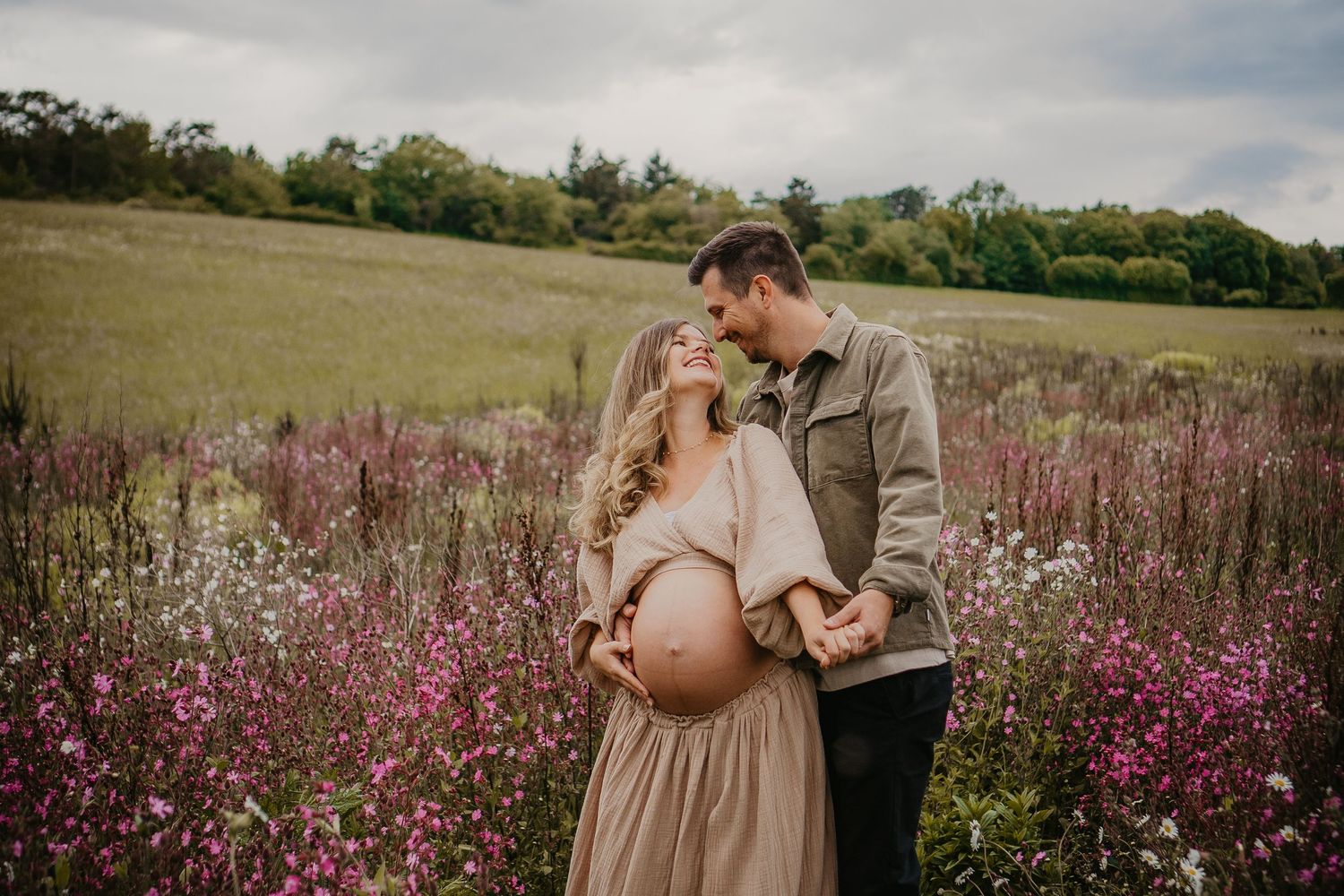 A couple shares a tender moment in a field of vibrant purple wildflowers on a cloudy afternoon.