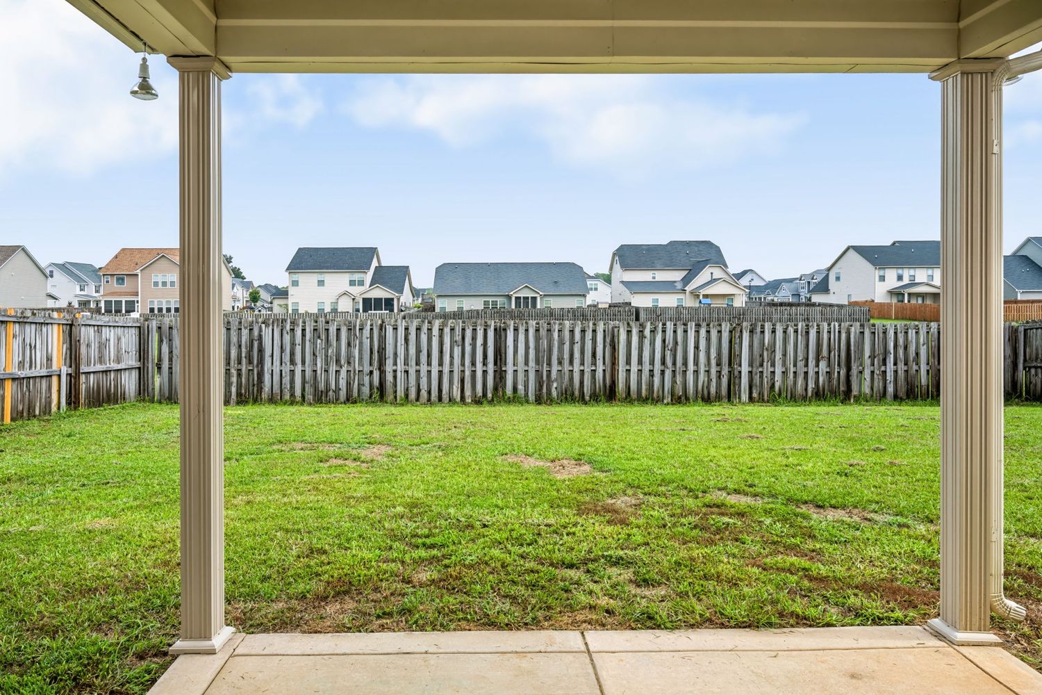 Real estate photograph of a covered patio overlooking the backyard