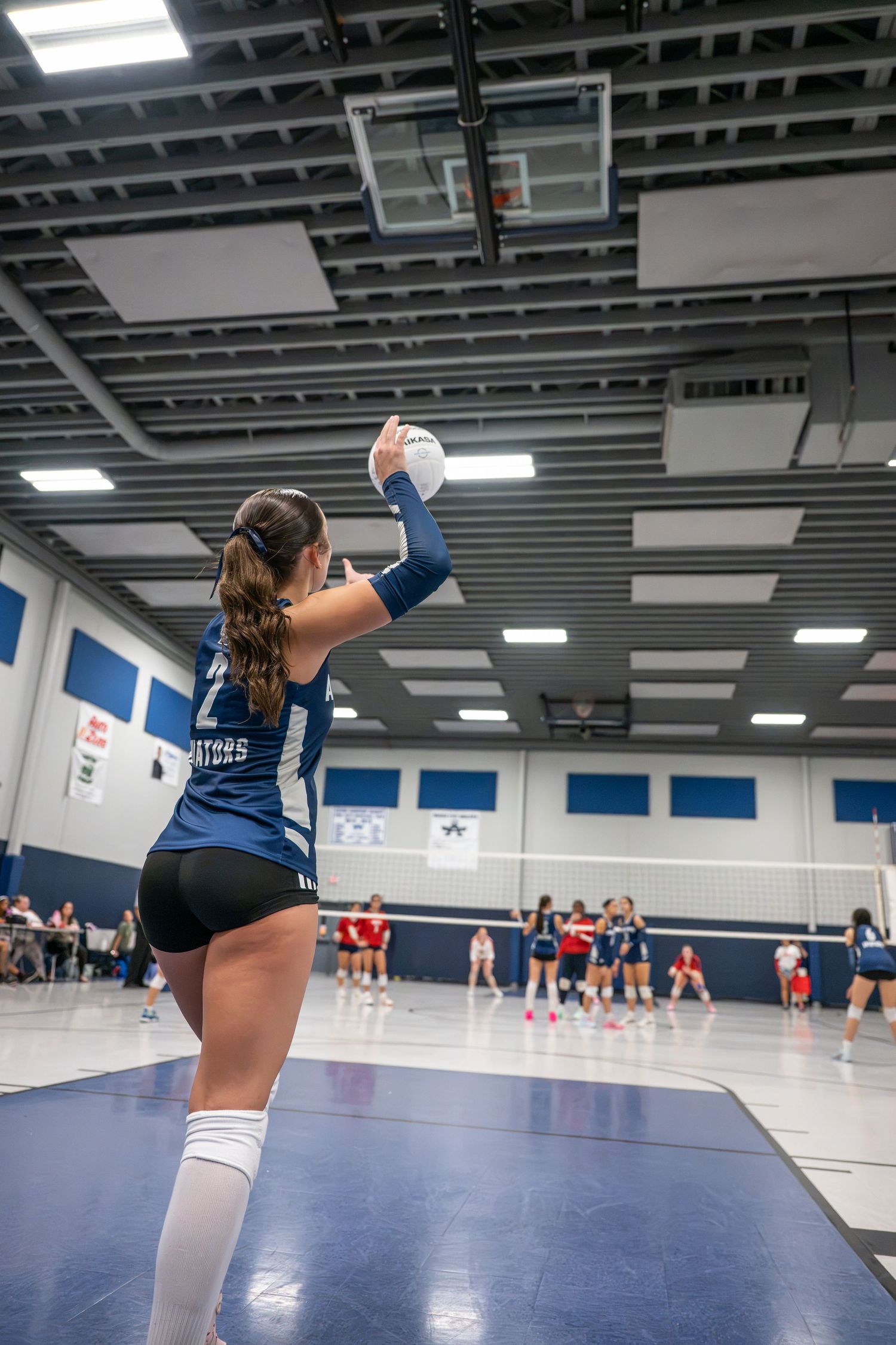 High school volleyball player serving during a match