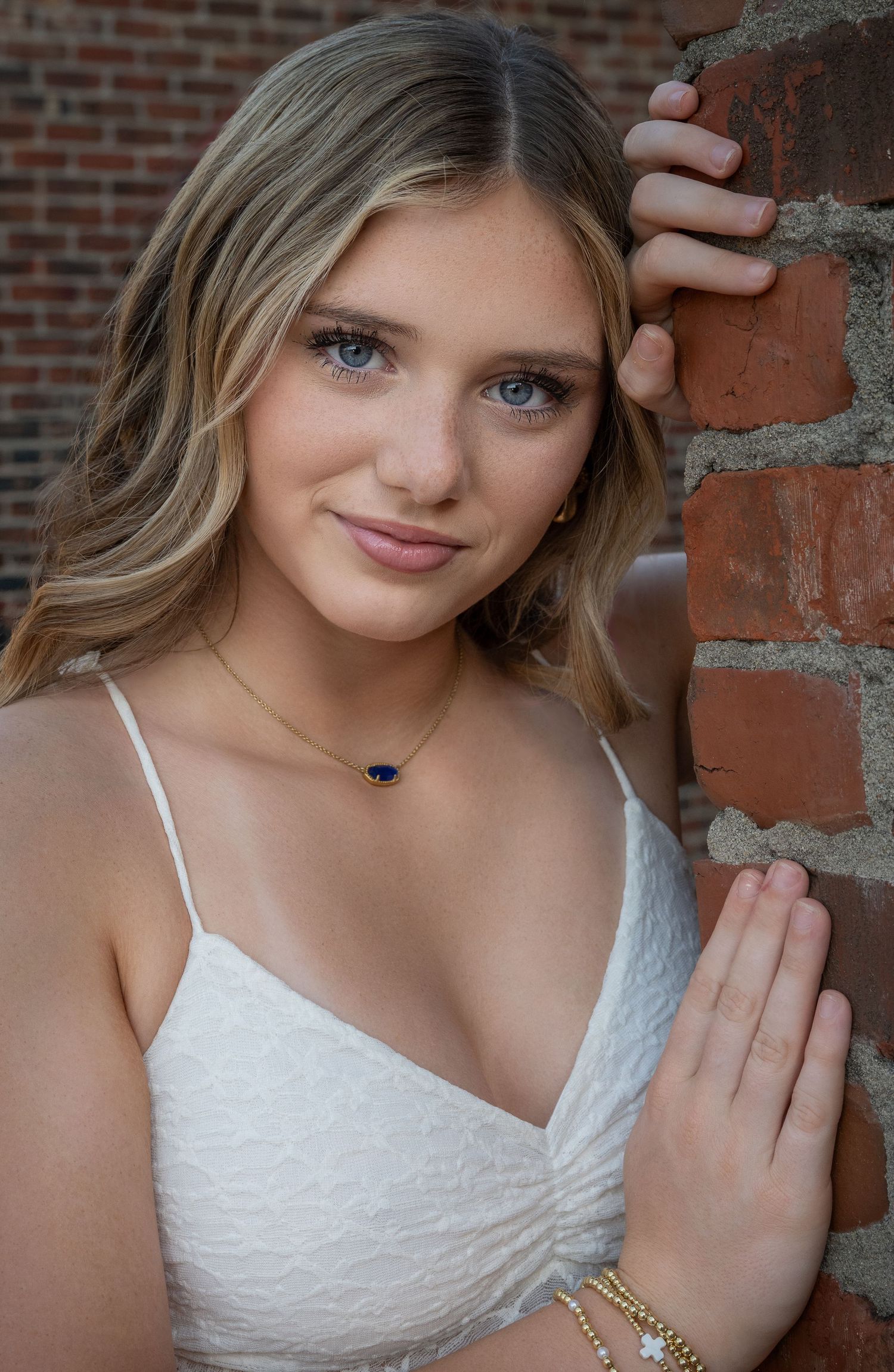 Outdoor senior portrait beside a brick wall