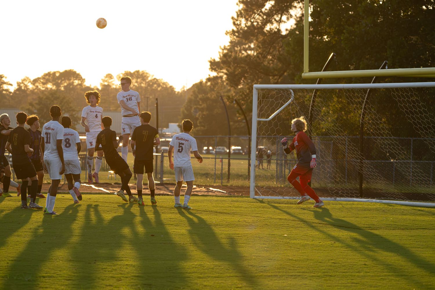 High school soccer action near the goal during golden hour