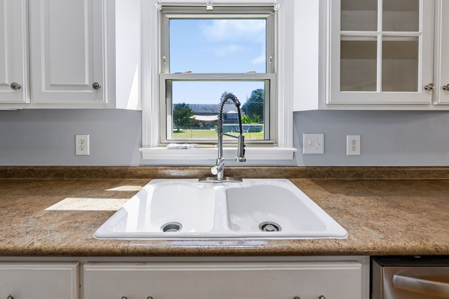 Real estate kitchen detail showing sink, cabinetry and backyard view