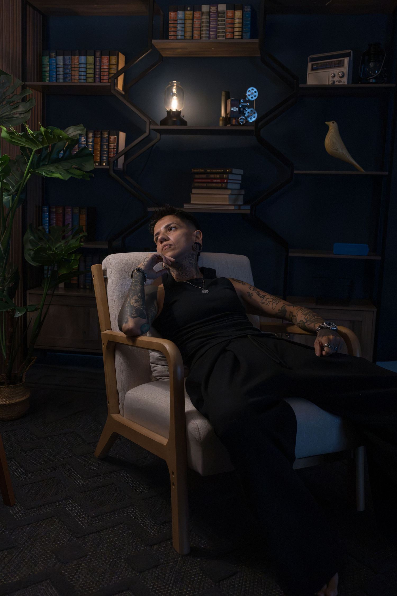 Dramatic environmental portrait of a person seated in a dark library setting