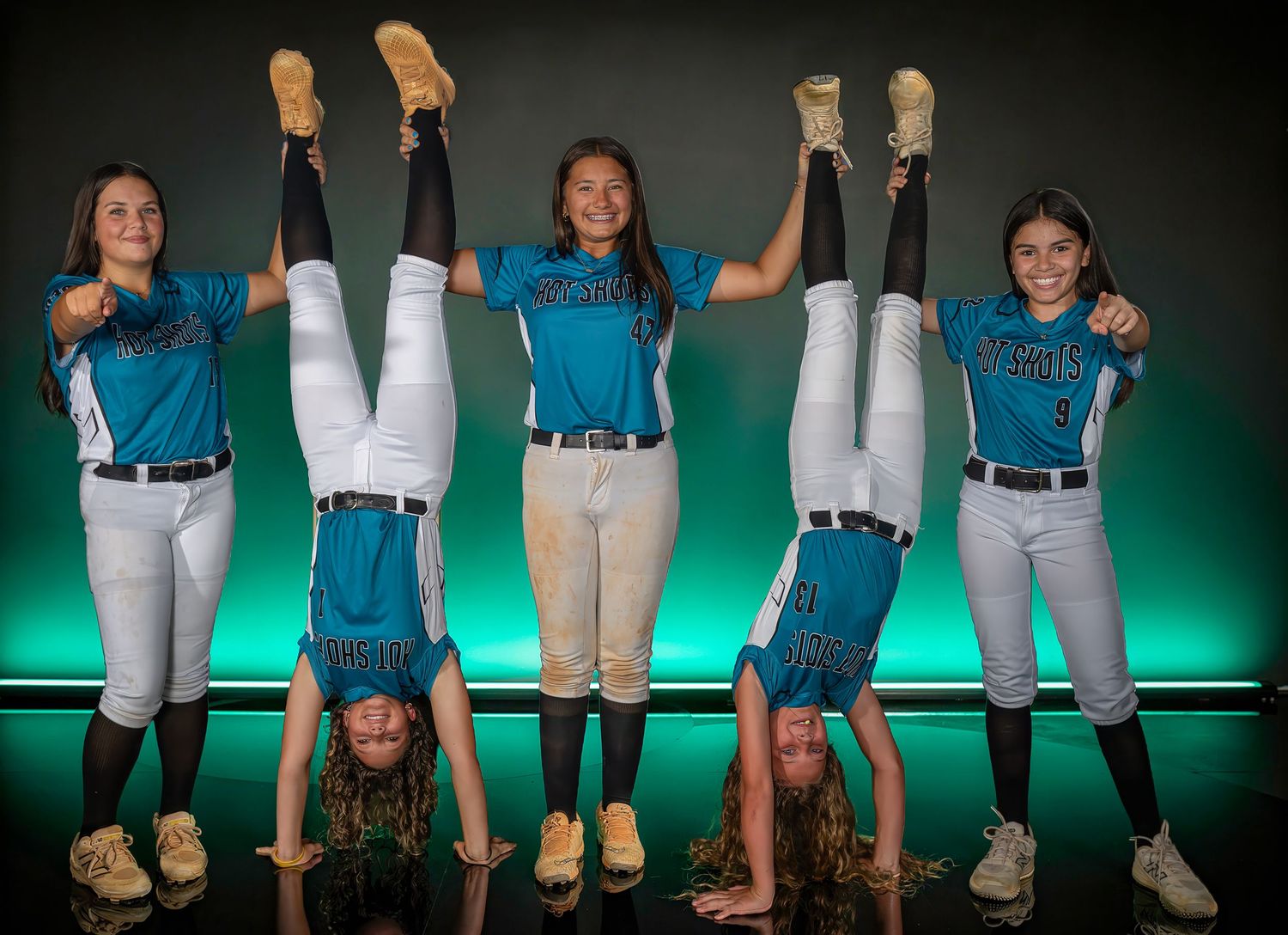 Creative softball team media day portrait with players posing upside down
