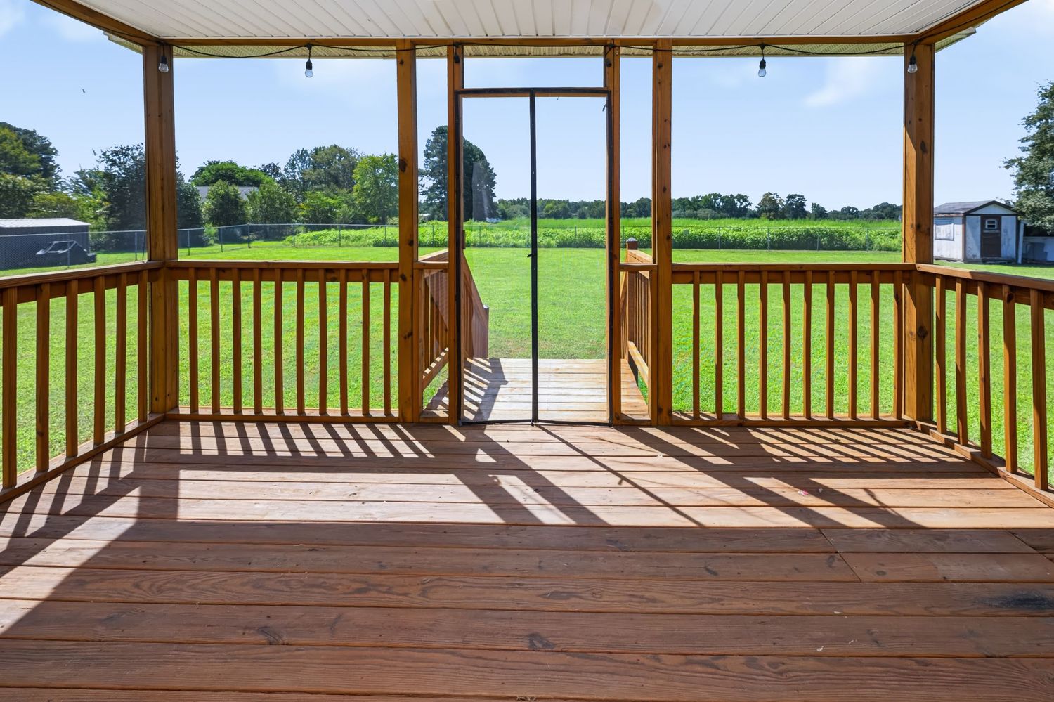 Real estate photograph of a screened porch overlooking the backyard