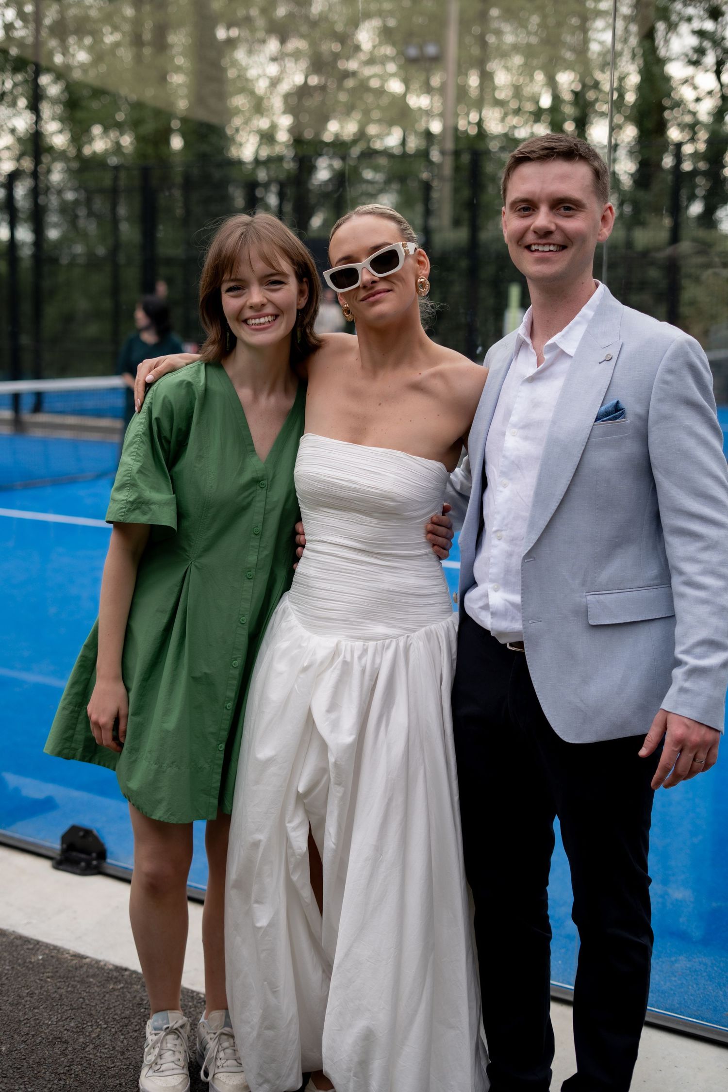 The bride and groom with a family member at their wedding