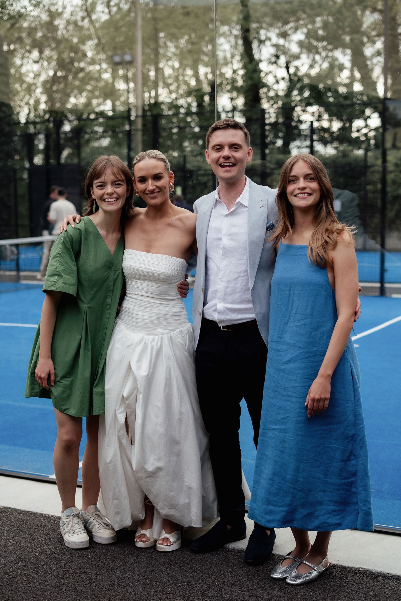 Bride and groom smiling with two friends in green and blue dresses