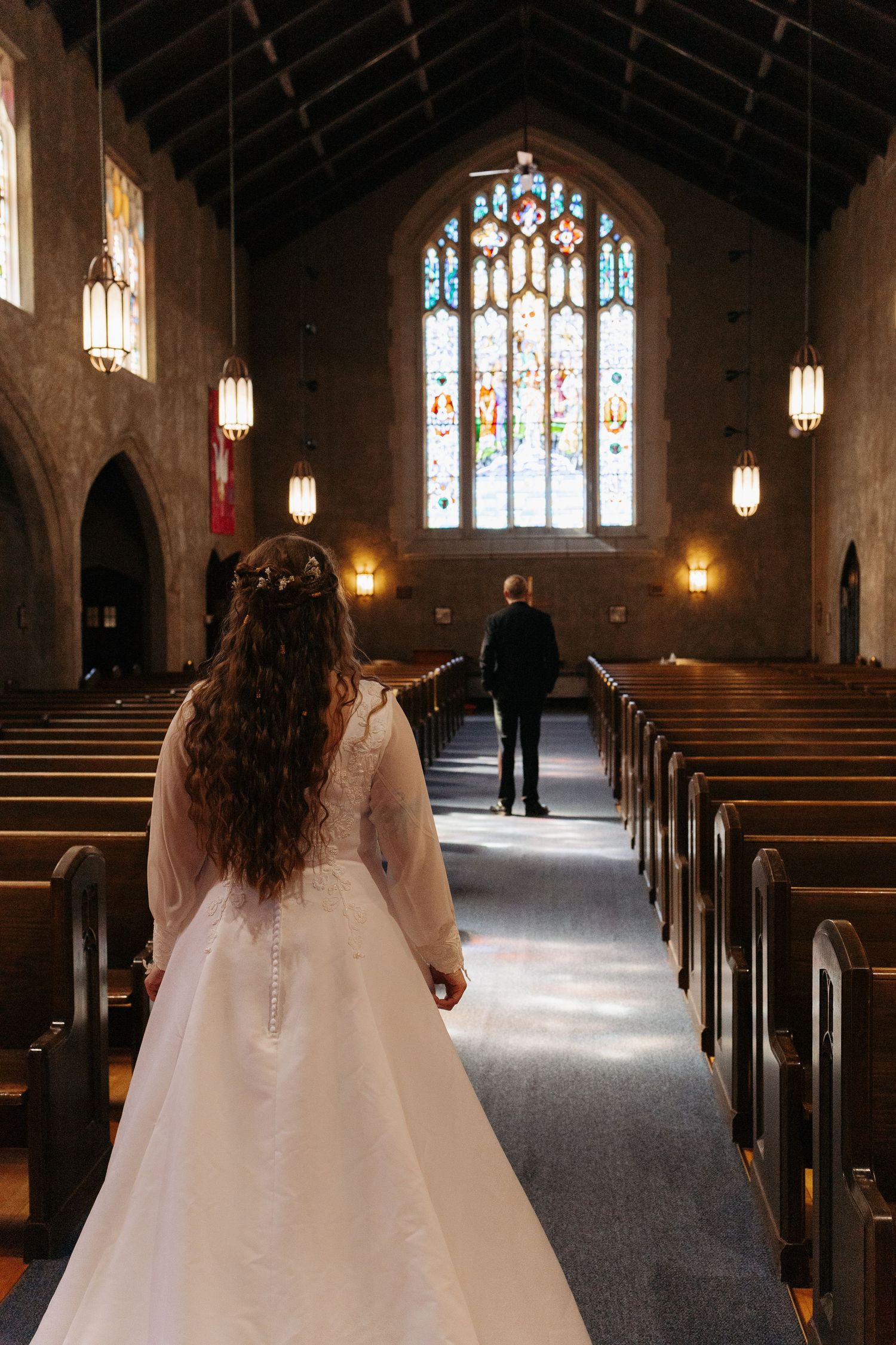 Bride walking down the aisle toward the groom in a stunning stone church.