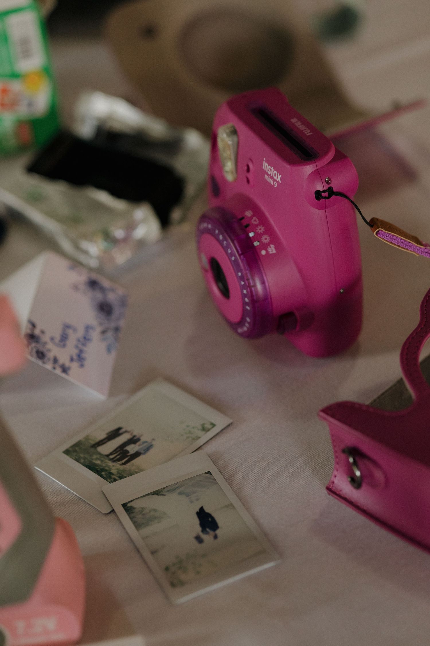 Pink Fujifilm Instax Mini 9 camera with printed photos on a table at a wedding reception.