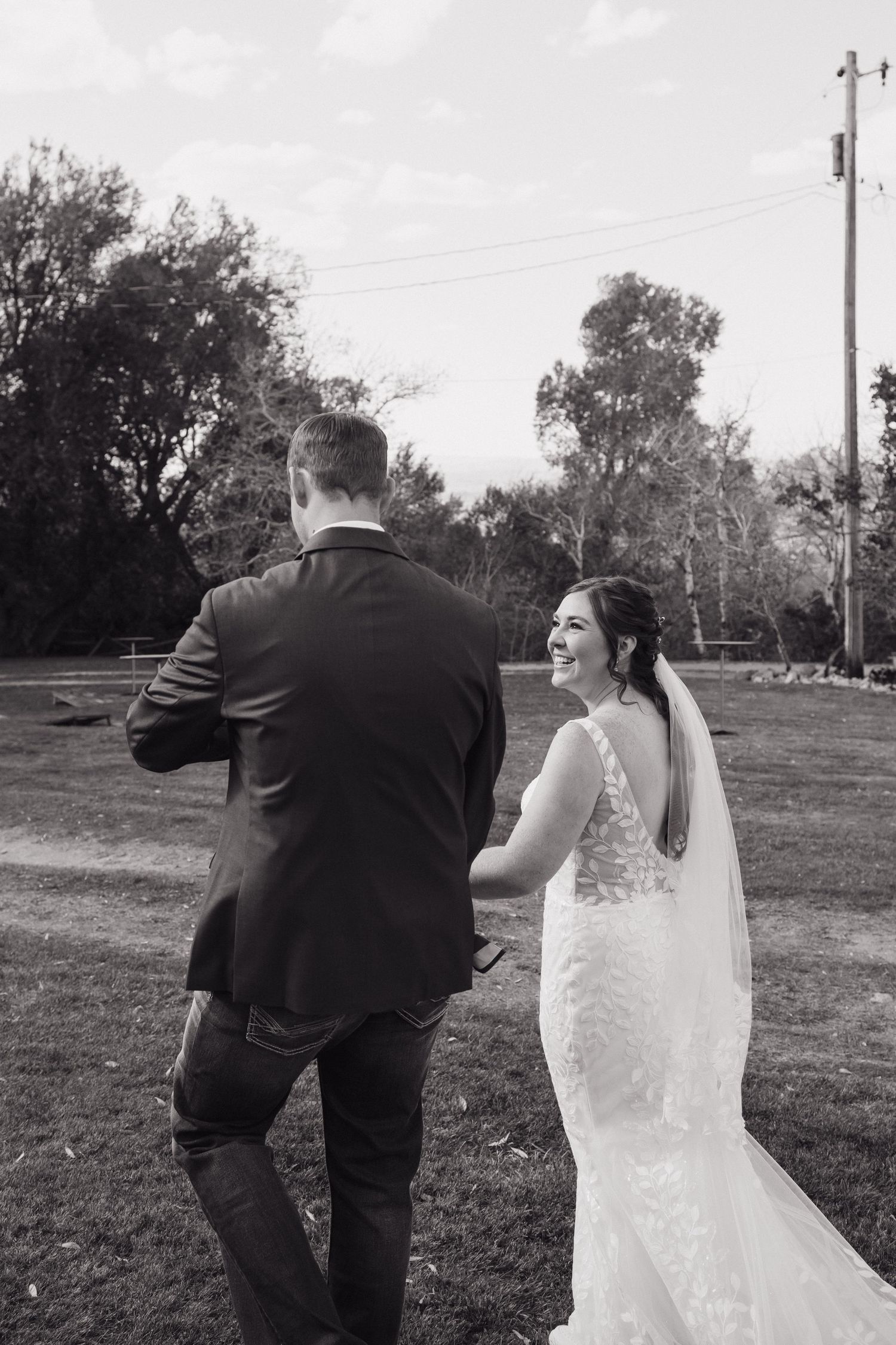Black and white photo of smiling bride and groom walking hand in hand outdoors. Wyoming wedding.
