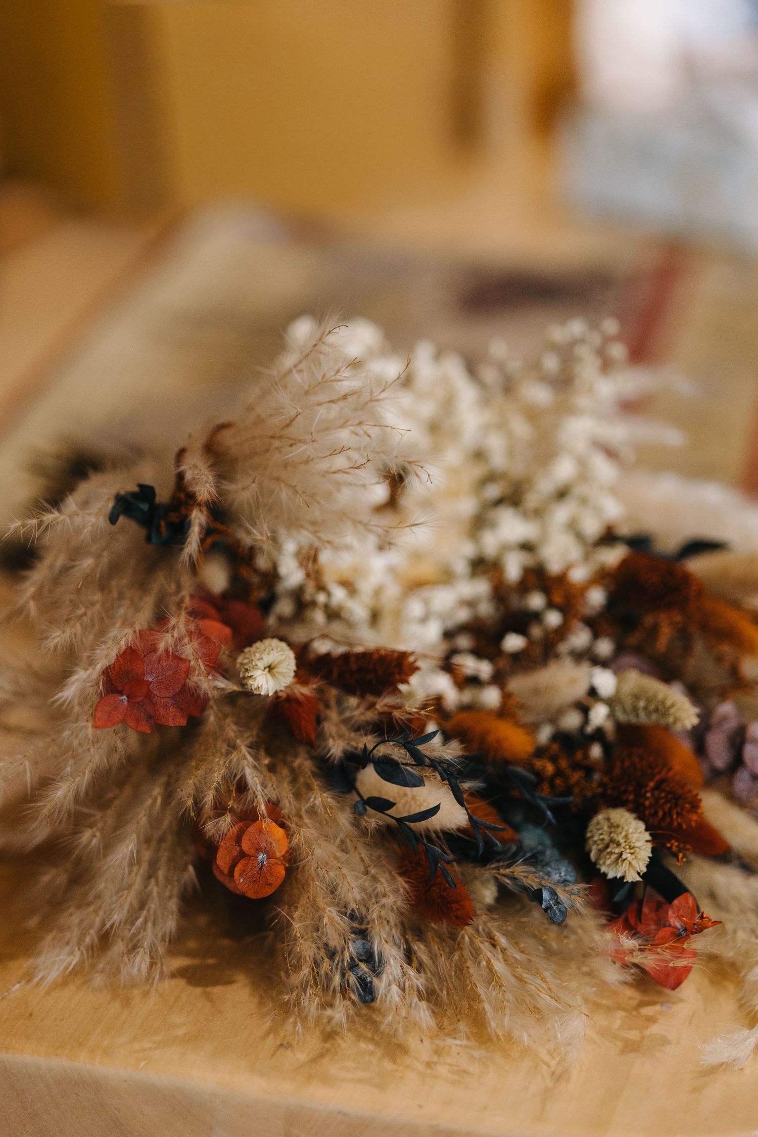Close-up of a boho dried flower arrangement with pampas grass, colorful blooms, and white flowers. Wyoming wedding