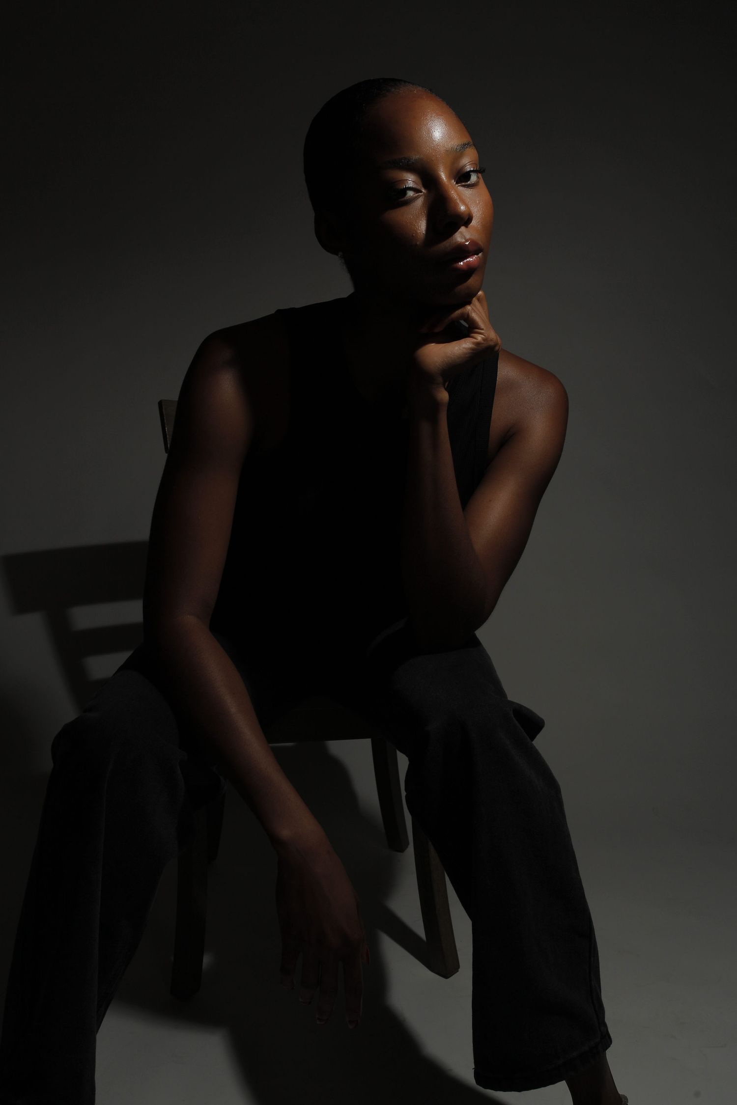 Artistic black and white portrait series showing dramatic poses against dark background with moody lighting.