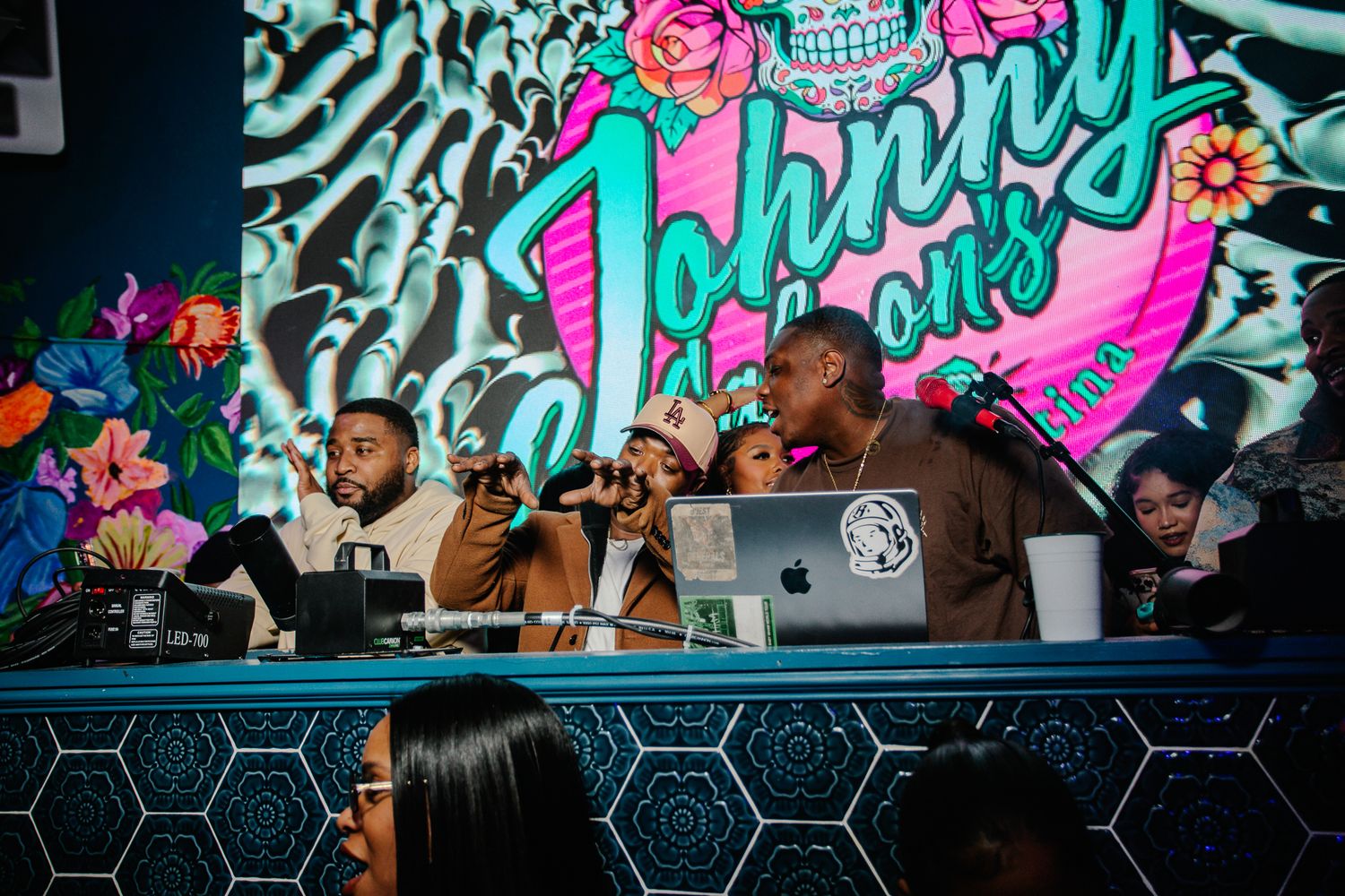 DJs performing at Johnny's colorful nightclub with vibrant skull mural backdrop and hexagon bar  with ray jay